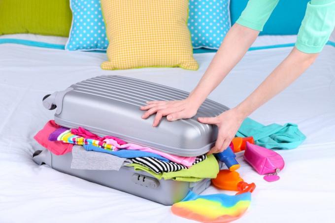 Girl samlar resväska på sängen närbild