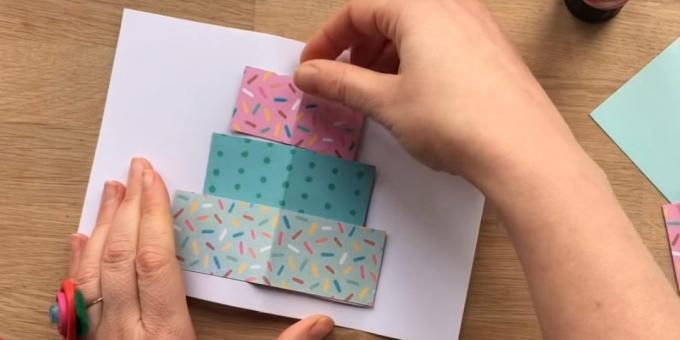 Klipp ut en rektangel av färgat papper tre skikt av den framtida storleken av kakan