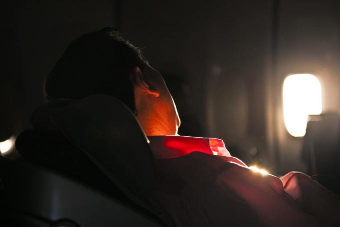 man sover i sätet på ett flygplan i soluppgång